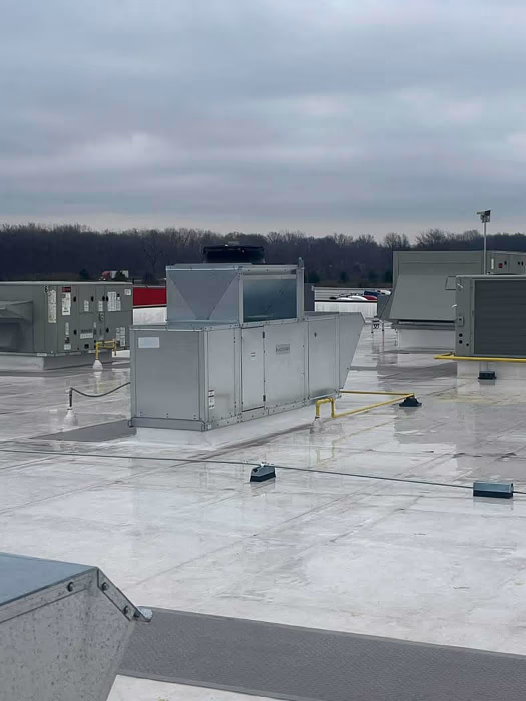 Metal HVAC units installed on a flat rooftop under an overcast sky.