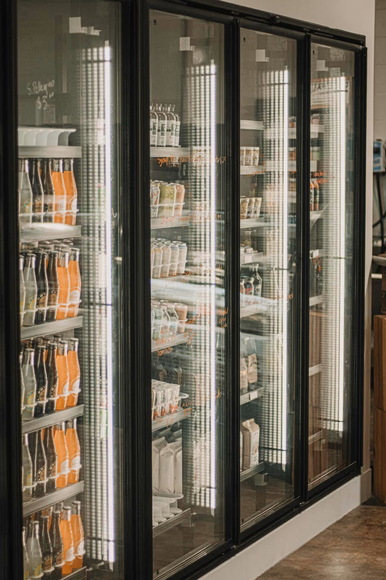 Refrigerated display with glass doors containing bottles of soda, cartons, and various packaged food items.